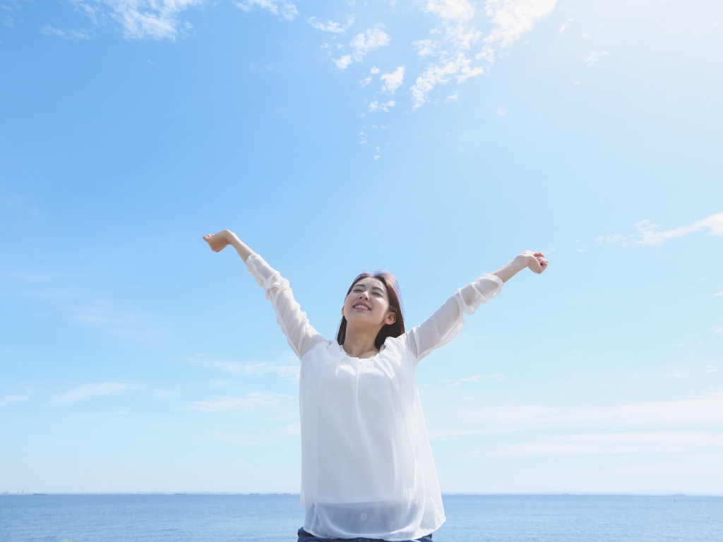 空の下で両手を広げる人物